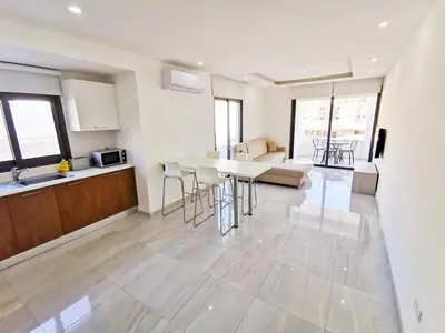 a kitchen and living room with a table and chairs at Vasilo Court Seaview City Apartment in Larnaka