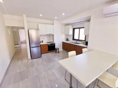 a kitchen with a table and a refrigerator at Vasilo Court Seaview City Apartment in Larnaka