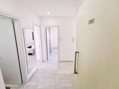a hallway with a mirror and a white door at Vasilo Court Seaview City Apartment in Larnaka