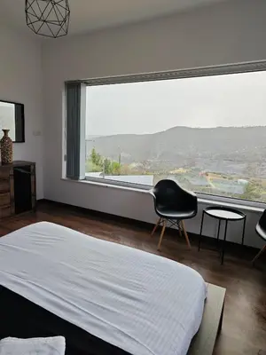 a bedroom with a bed and a chair and a large window at Maximos Luxury Villa Monagri Limassol in Limassol