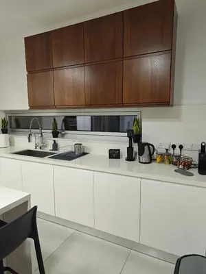 a kitchen with white counters and wooden cabinets at Maximos Luxury Villa Monagri Limassol in Limassol