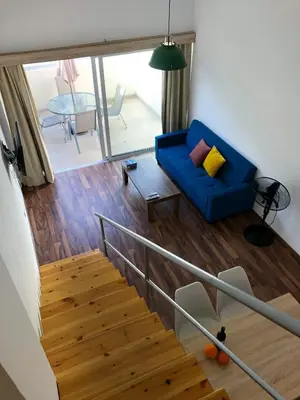 a living room with a blue couch and a staircase at Cozy Loft Apartment in Ayia Napa
