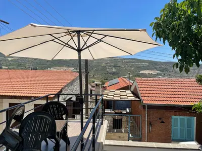a white umbrella sitting on top of a balcony at Omodos Katoi Holiday Homes in Omodos