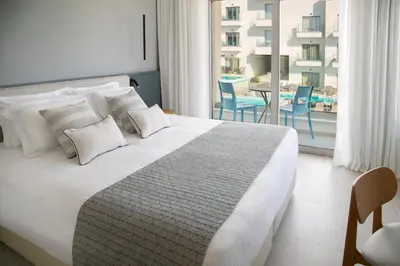 a bedroom with a bed and a balcony with a table at Atlantica Aqua Blue in Protaras