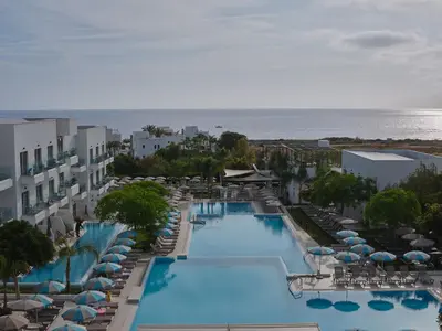 an aerial view of a resort swimming pool with umbrellas and the ocean at Atlantica Aqua Blue in Protaras