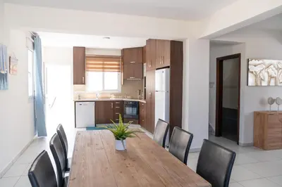 a kitchen and dining room with a wooden table and chairs at Dafni Villa Ekaterina 3 bdrm in Protaras