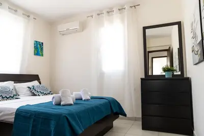 a bedroom with a bed with a blue blanket and a mirror at Dafni Villa Ekaterina 3 bdrm in Protaras