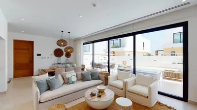 a living room with white furniture and a large window at Periyiali Konnos Villas Beach Resort in Protaras