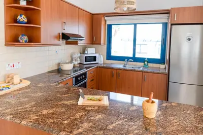 a kitchen with a granite counter top and a refrigerator at St Nicolaos Villa Ekaterina 3 bdrm in Protaras