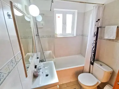 a bathroom with a sink and a toilet and a tub at License to Chill Apartment in Larnaka