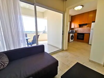a living room with a couch and a kitchen at License to Chill Apartment in Larnaka