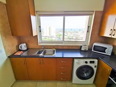 a kitchen with a sink and a washing machine at License to Chill Apartment in Larnaka