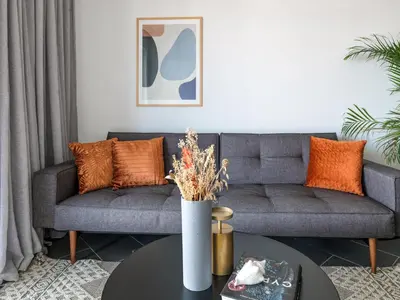 a living room with a gray couch and orange pillows at LIV URBAN Suites in Larnaka