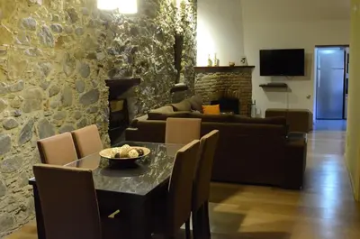 a living room with a table and a stone wall at To Kastri in Kalopanayiotis