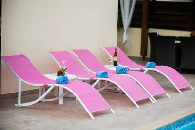 a group of pink chairs and a table with a bottle of wine at Luxury Villa Regina in Protaras