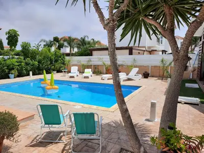 a swimming pool with two lawn chairs and palm trees at Villa Anastassia in Ayia Napa