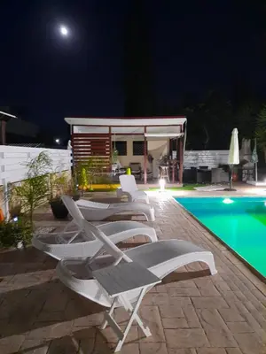 a row of lounge chairs next to a swimming pool at night at Villa Anastassia in Ayia Napa