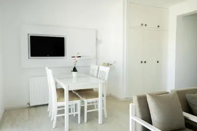 a white dining room with a white table and chairs at Liquid Hotel Apartments in Ayia Napa