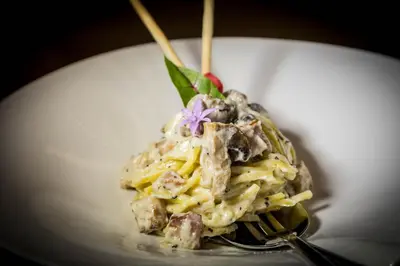 a plate of food with pasta and a purple flower at Liquid Hotel Apartments in Ayia Napa