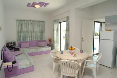 a kitchen and living room with a table and a couch at Sunbay Apartments in Pyla