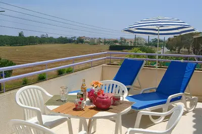 a table and chairs on a balcony with an umbrella at Sunbay Apartments in Pyla