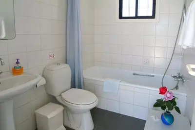 a white bathroom with a toilet and a bath tub at Sunbay Apartments in Pyla