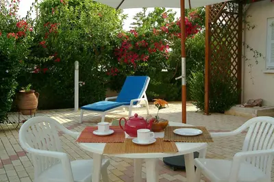 a table and chairs with a blue chair and an umbrella at Sunbay Apartments in Pyla