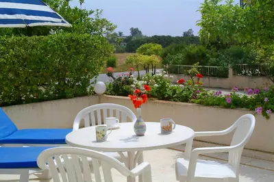 a table with two chairs and a vase with flowers at Sunbay Apartments in Pyla