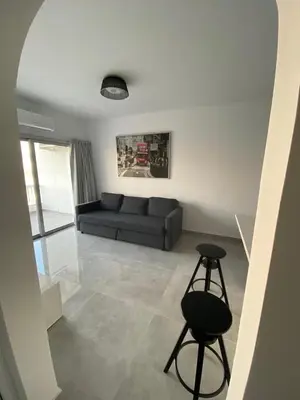 a living room with a black couch and a stool at Greco 1 Bedroom Apartment in Limassol