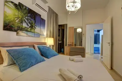 a bedroom with a large white bed with blue pillows at SunnyVillas: 4BR Villa☆Private Pool + Jacuzzi - Villa Amelie in Protaras