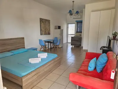 a bedroom with a bed and a red couch at Magic Sea Apartments in Larnaka