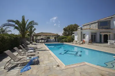 a swimming pool with chairs and a house at Protaras Villa Mazeri in Protaras