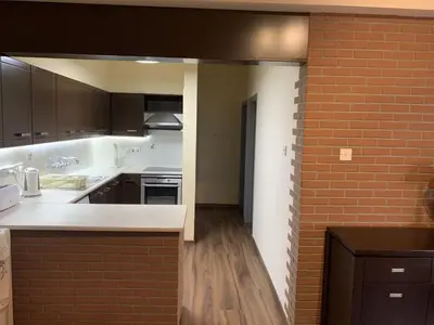 a kitchen with white counters and a brick wall at Kika Court 2 in Paralimni