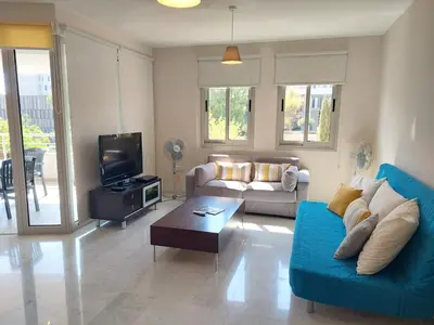 a living room with a blue couch and a tv at Amathousa Coastal Heights D202 in Limassol