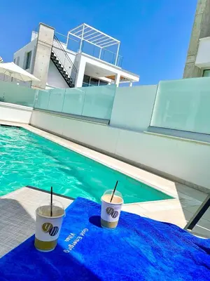 two cups on a blue towel next to a swimming pool at Imperial Jade Villas Gold Emerging Villas 2 in Protaras