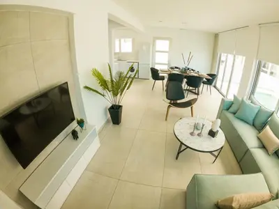 a living room with a couch and a tv and a table at Imperial Jade Villas Gold Emerging Villas 2 in Protaras