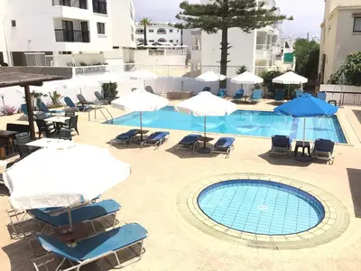 a swimming pool with chairs and umbrellas at Florea Hotel Apartments in Ayia Napa