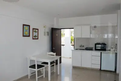 a kitchen with white cabinets and a table and chairs at Florea Hotel Apartments in Ayia Napa