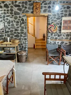 a room with a stone wall with tables and chairs at The Old Coffeehouse in Kalopanayiotis