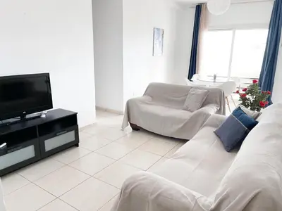 a living room with a white couch and a tv at Apartment Capella, Larnaca in Larnaka