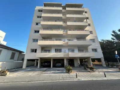 a large white apartment building with a parking lot at Apartment Capella, Larnaca in Larnaka