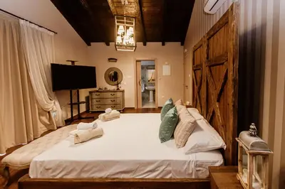a bedroom with a large white bed and a television at Grand Mansion Countryhouse & Spa in Phrenaros