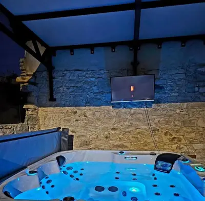 a bath tub in a room with a tv on a wall at The Stonehouse Suites with Private Bath Spas in Limassol