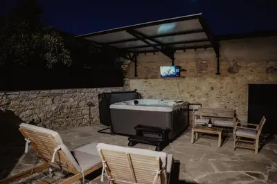 a patio with a tub and chairs and a tv at The Stonehouse Suites with Private Bath Spas in Limassol