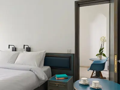 a bedroom with a bed and a blue chair and a table at TSANotel in Limassol