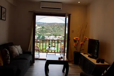 a living room with a door open to a balcony at skeleas 10 in Pissouri