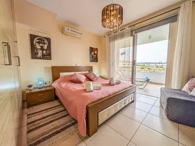 a bedroom with a large bed and a balcony at NISSI BEACH POOL VIEW APARTMENT FREE WIFI in Ayia Napa