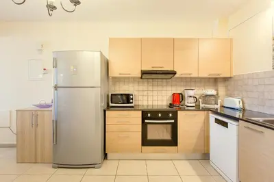 a kitchen with a stainless steel refrigerator and wooden cabinets at NISSI BEACH POOL VIEW APARTMENT FREE WIFI in Ayia Napa