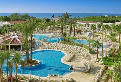 a resort with a large pool with chairs and palm trees at Olympic Lagoon Resort Ayia Napa in Ayia Napa