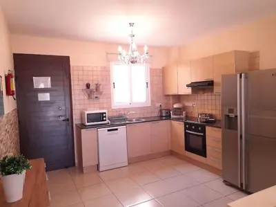 a large kitchen with a refrigerator and a window at NISSI BEACH Apt 7 BIG VERANDA AND FREE WIFI in Ayia Napa